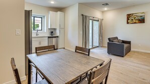 A spacious living area with a dining table, a sofa, and a kitchen in the background.