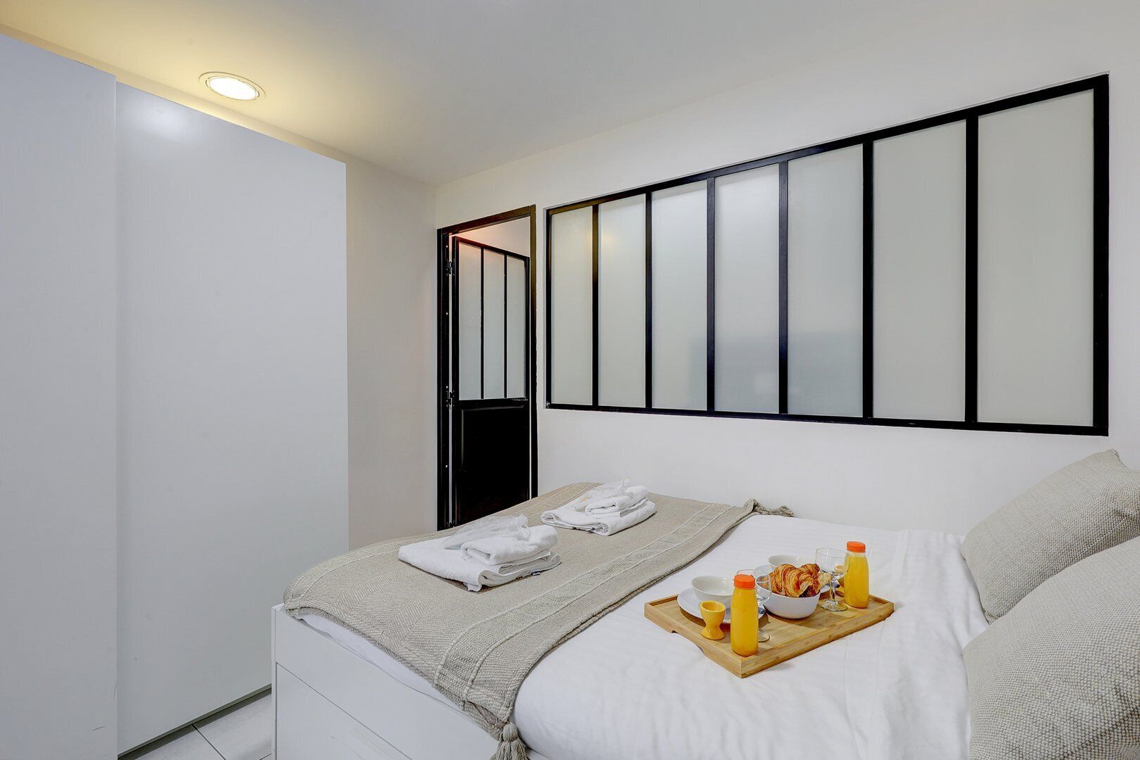 Une chambre d’hôtel avec un lit, un plateau contenant des articles pour le petit-déjeuner et une fenêtre avec des stores.