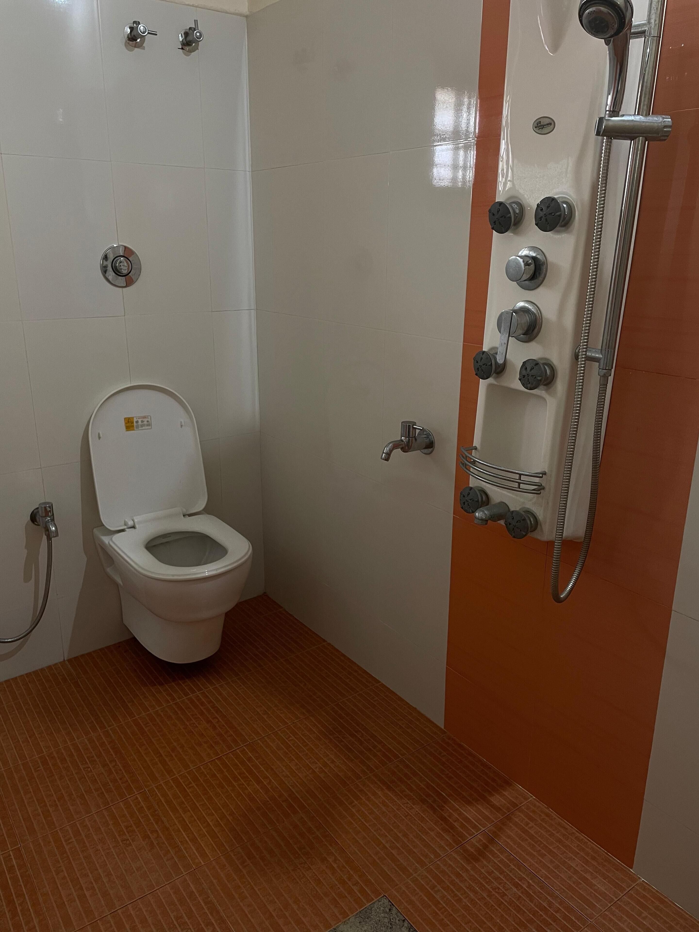 Une salle de bain équipée de toilettes, d’une douche et d’un sèche-mains.