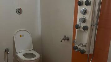 Une salle de bain équipée de toilettes, d’une douche et d’un sèche-mains.