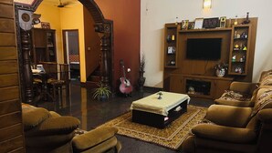 Uma sala de estar com sofá, mesa de centro, televisão e lareira.