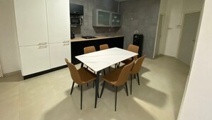A compact kitchen with a dining area, white cabinets, a microwave, and a built-in oven.