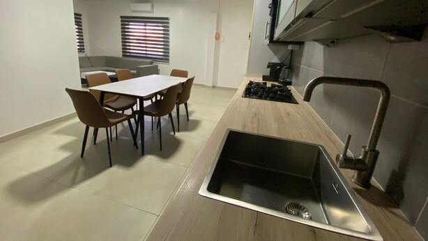 A compact kitchen with a central island, a dining table with chairs, and a built-in sink.
