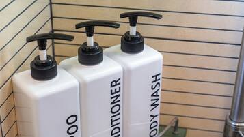 Tres botellas blancas con dosificadores negros, etiquetadas 'SHOWER BATH', 'SHOWER BATH' y 'SHOWER BATH'.