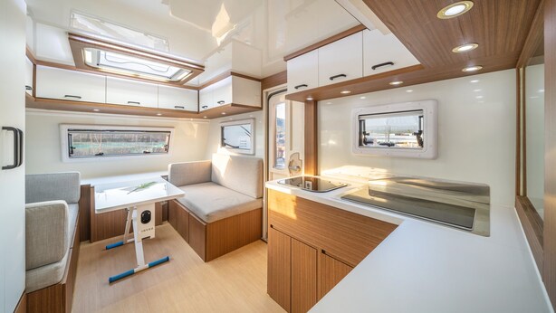 A compact RV interior with a kitchenette, seating area, and a window providing a view. - Goseong Hoostay Caravan Pension (Goseong)