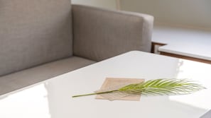 Una mesa blanca con una sola hoja de palma y un pedazo de papel encima.