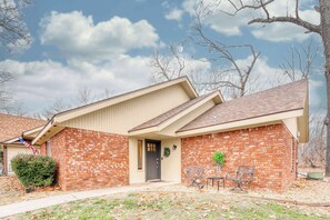 A two-story house with a brick facade, a front porch with a bench, and a small front yard.