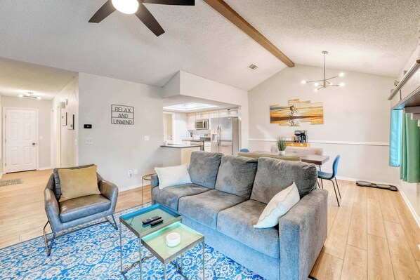A modern living room with a grey sofa, a coffee table, and a patterned rug.