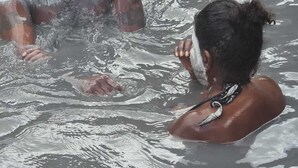 Two people in a body of water, possibly a river or lake, with one person partially submerged.