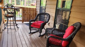 Eine Veranda mit Korbstühlen und einem Tisch.