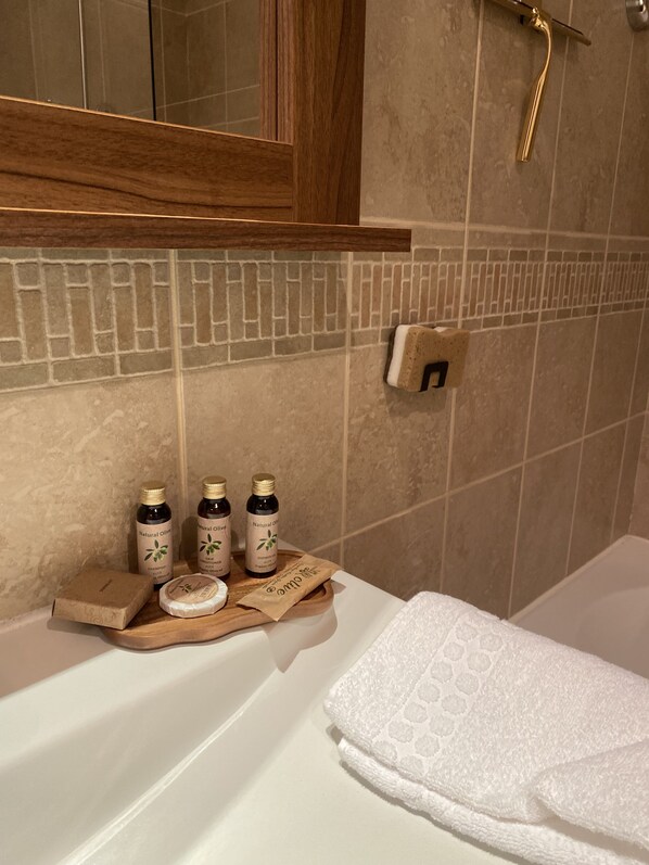 A bathroom with a wooden shelf holding three bottles of natural olive shampoo, a bar of soap, and a towel. - Magnificent apartment right in the center, walking distance to shops and ski slopes! Terrace (Isola)