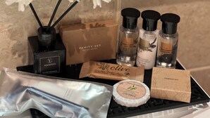 A tray with various toiletries including a fire extinguisher, a vanity set, perfume bottles, a sewing kit, and a bar of soap.