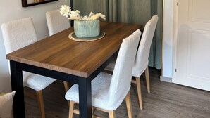 A dining area with a wooden table, white chairs, and a decorative vase.