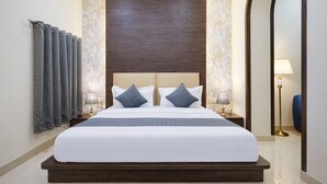 A modern hotel room with a large bed, two bedside tables with lamps, a mirror, and a view of the hallway. - Shyama inn by Rivlet  (New Delhi)