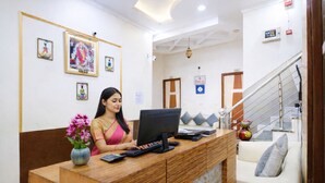 A reception desk with a computer, a vase of flowers, and framed artwork on the wall. - Shyama inn by Rivlet  (New Delhi)