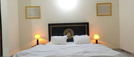 Une chambre d’hôtel avec un grand lit, deux lampes de chevet et une tête de lit décorative.