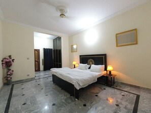 A hotel room with a bed, two bedside lamps, a mirror, and a decorative wall piece. - Room-room in Asga Best Versace Guesthou (Rawalpindi)