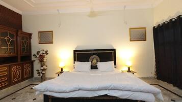 A neatly made bed with a dark headboard and white bedding, flanked by two bedside lamps.
