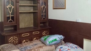 Ένα υπνοδωμάτιο με δύο μονά κρεβάτια, μια ξύλινη ντουλάπα και έναν ανεμιστήρα οροφής.