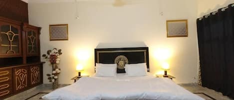 A neatly made bed with a black headboard and white bedding, flanked by two bedside lamps.