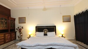 A neatly made bed with a dark headboard and white bedding, flanked by two bedside lamps. - Room-serene Guest Room Retreat in Rawalp (Rawalpindi)