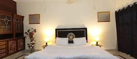 A neatly made bed with a dark headboard and white bedding, flanked by two bedside lamps.