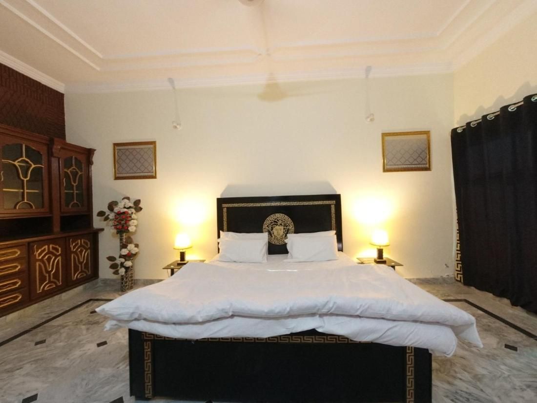 Una cama bien hecha con un cabecero negro y ropa de cama blanca, con dos lámparas de noche a cada lado.