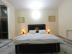 Habitación de hotel con cama, dos lámparas de noche, un cabecero decorativo y suelo de mármol.