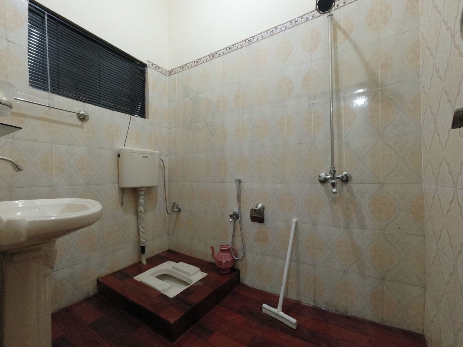 A small bathroom with a toilet, sink, shower, and mop.