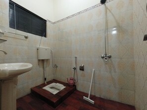 Ein kleines Badezimmer mit Toilette, Waschbecken, Dusche und einem Mopp.