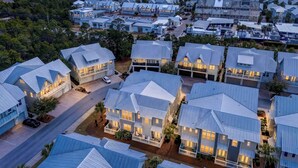 A coastal residential area with modern houses featuring multiple stories, large windows, and a prominent waterfront view.