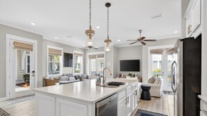 A modern kitchen with a large island, white cabinetry, and a black refrigerator.