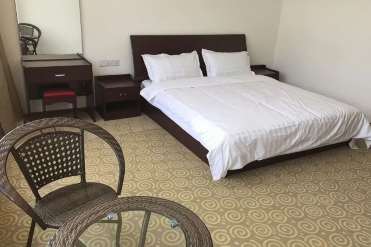 A hotel room with a bed, a chair, a desk, and a nightstand.
