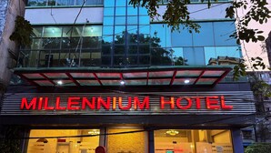 L'esterno del Millennium Hotel, con un cartello ben visibile, una facciata in vetro e un tendone rosso.
