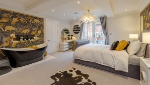 A modern bedroom with a large bed, a freestanding bathtub, and a vanity with a mirror. - Luxury Apartment in 18th century listed Hotel conversion (Farnham)