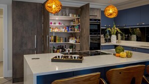 A modern kitchen with a central island, wooden chairs, and pendant lighting. - Luxury Apartment in 18th century listed Hotel conversion (Farnham)