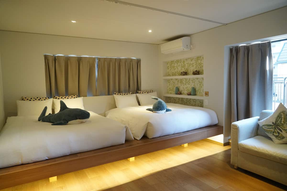 Une chambre avec deux lits, un canapé et une fenêtre avec des rideaux.