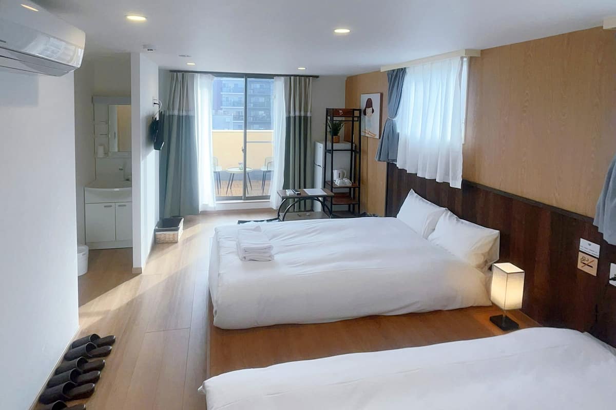 Une chambre d’hôtel avec deux lits, un balcon avec une table et des chaises, et une vue sur la ville.