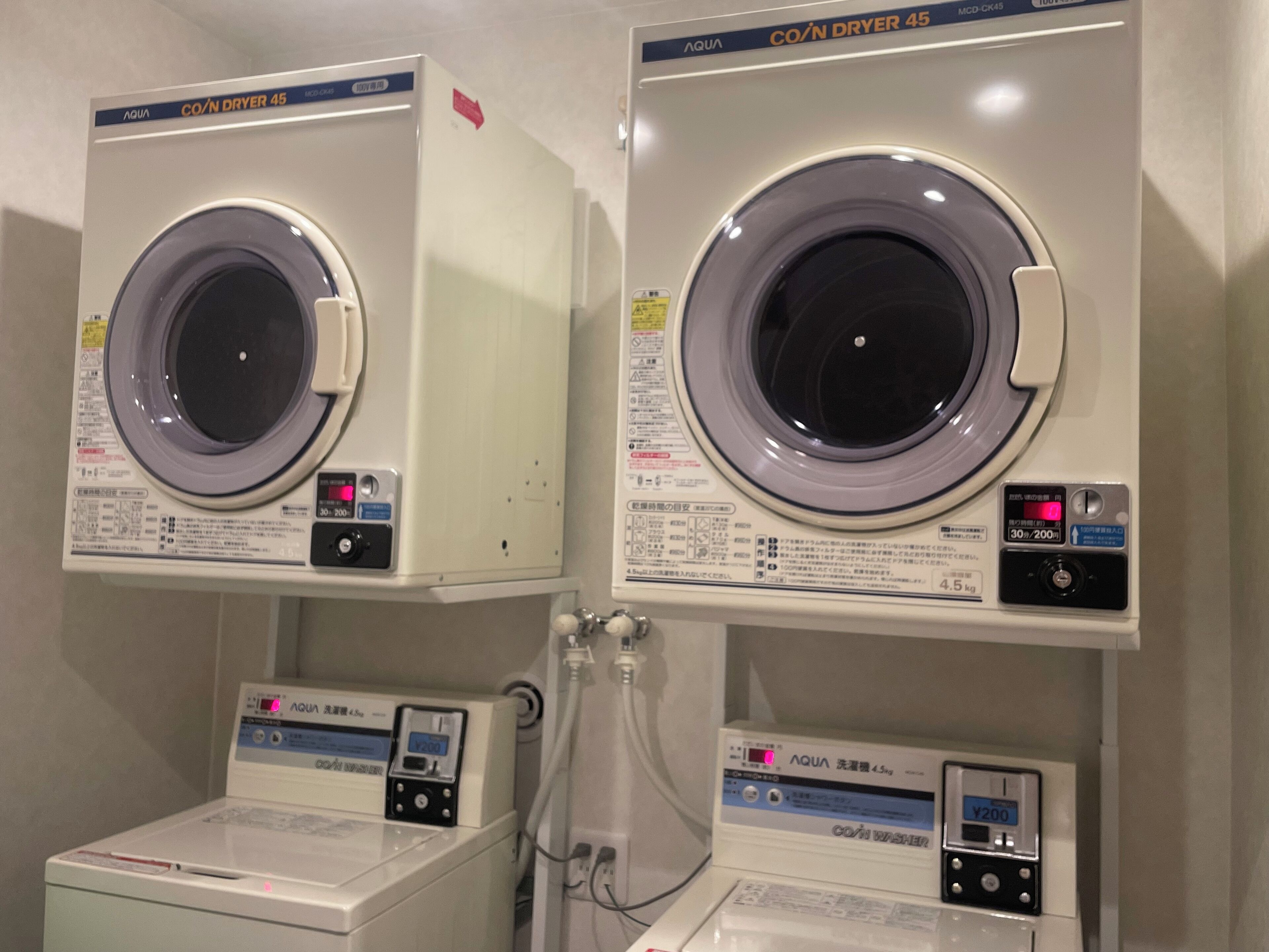 Two front-loading washing machines with digital displays, a dryer, and a washing machine with a control panel.