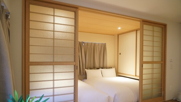 A traditional Japanese-style room with sliding doors, a bed with white bedding, and a potted plant. - softlight inn Asakusa Tokyo (Tokyo)