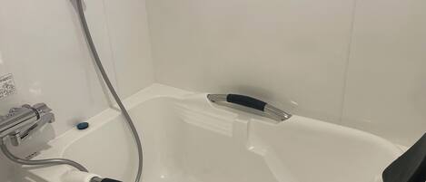 Una bañera blanca con dos manijas negras, un grifo de cromo y un panel de control con un botón azul.