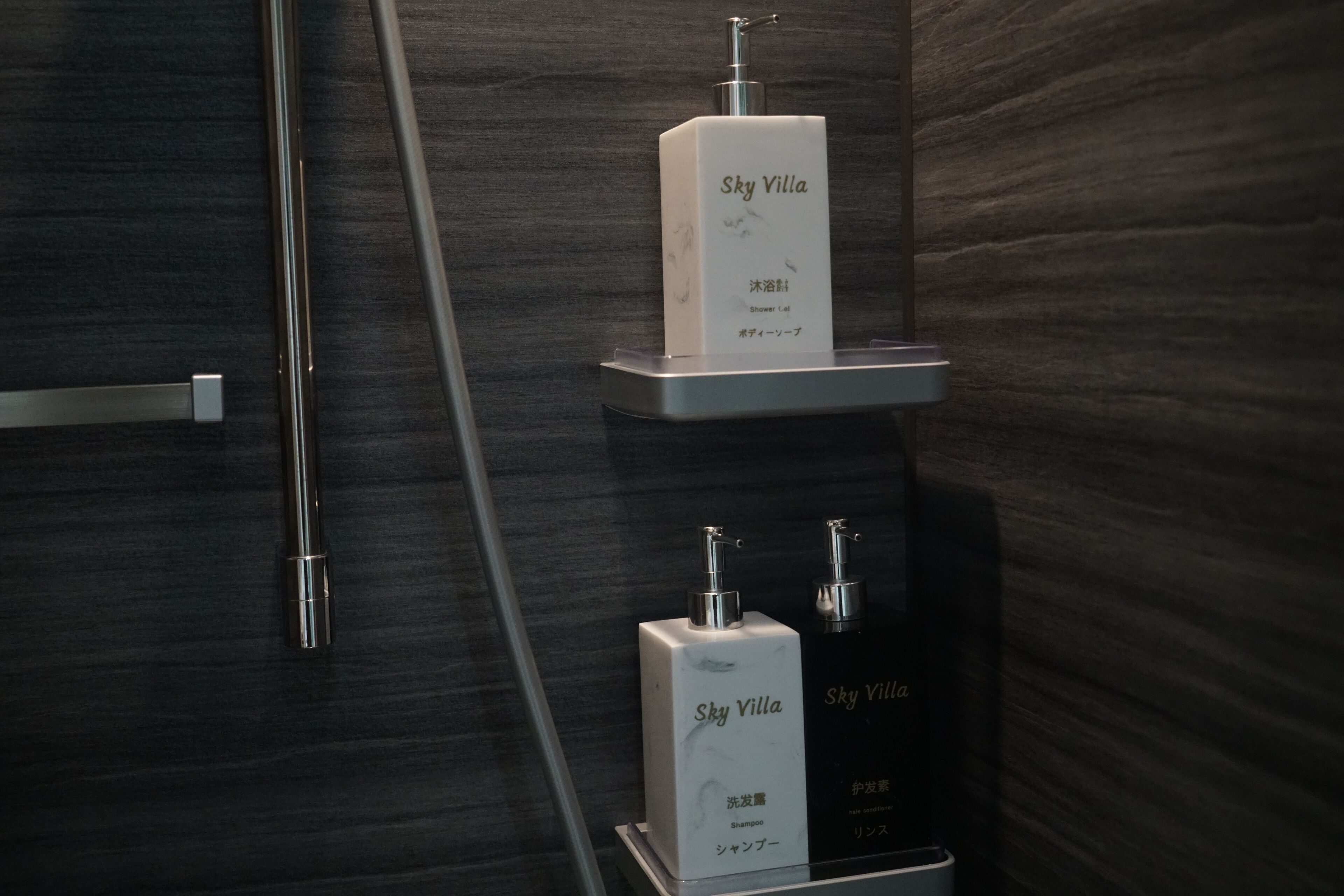 A bathroom with a dark wood wall, a metal towel rack, and two white bottles labeled 'Sky Villa' on a shelf.