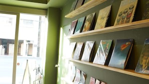 A room with a green wall and wooden shelves displaying various books and magazines. - softlight inn Asakusa Tokyo (Tokyo)