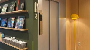 A hotel room with a wooden floor, a bookshelf with books, a desk with a lamp, and a door with a phone. - softlight inn Asakusa Tokyo (Tokyo)