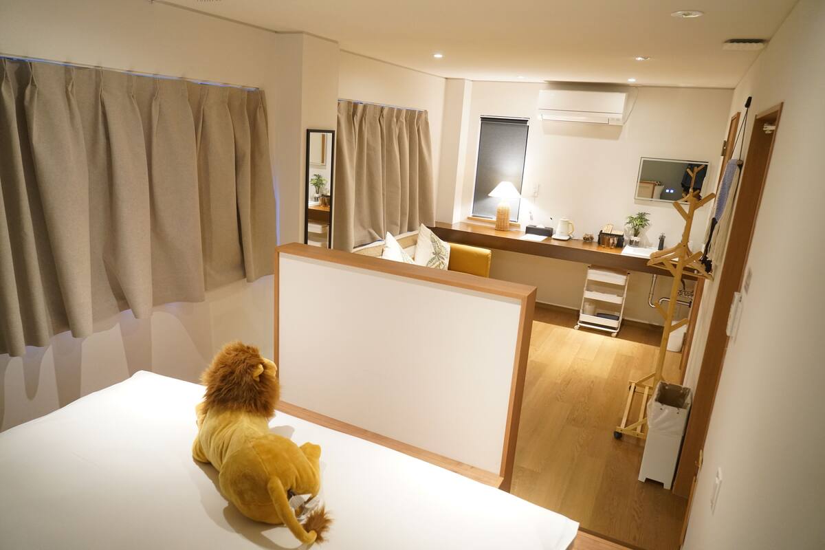 Une chambre d’hôtel avec un lit, un bureau, une chaise, une lampe et un miroir.