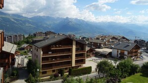 Un hotel de varios pisos con balcones, rodeado de montañas y un cielo despejado.