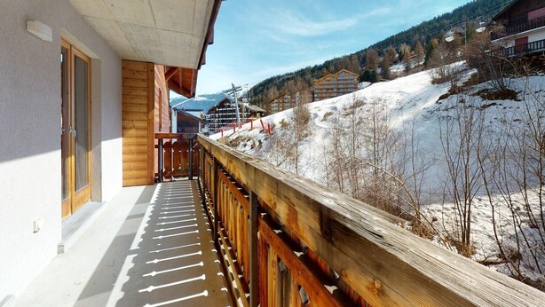 Ein Holzbalkon mit Blick auf eine verschneite Berglandschaft.