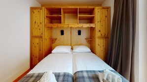 Ein Zimmer mit zwei Betten, einem Holzkopfteil und einem Vorhang.
