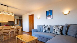 A modern living room with a sofa, a wooden coffee table, and a dining area with a table and chairs. There is a kitchen visible in the background. - Spacious apartment with view (Haute-Nendaz)