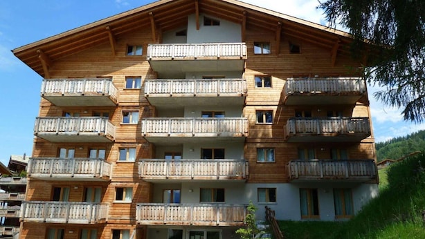 A multi-story wooden building with balconies, likely a hotel or guesthouse. - Spacious apartment with view (Haute-Nendaz)